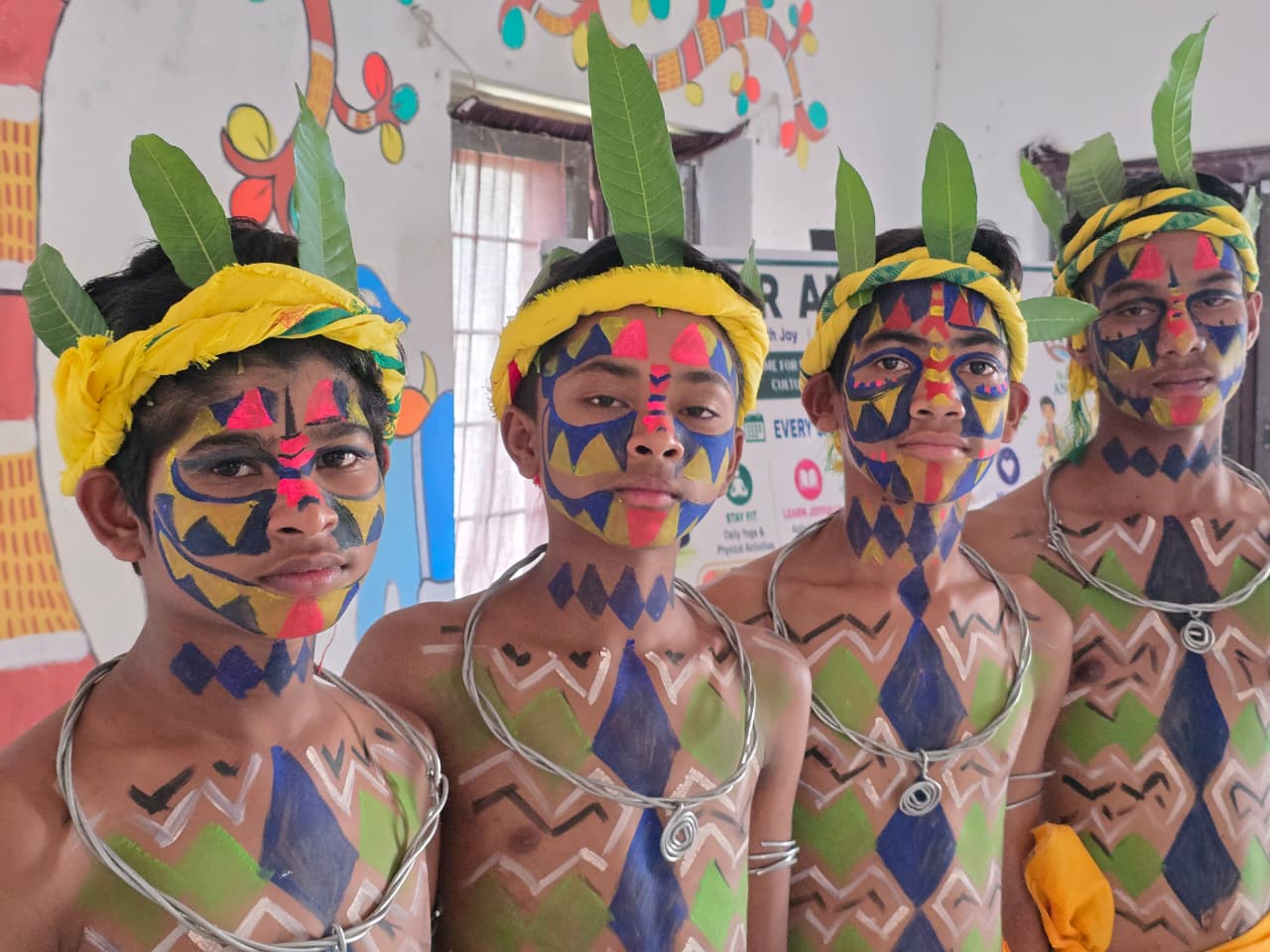 EMRS Ananthagiri students in traditional tribal face and body paint with leaf headgear before a cultural performance